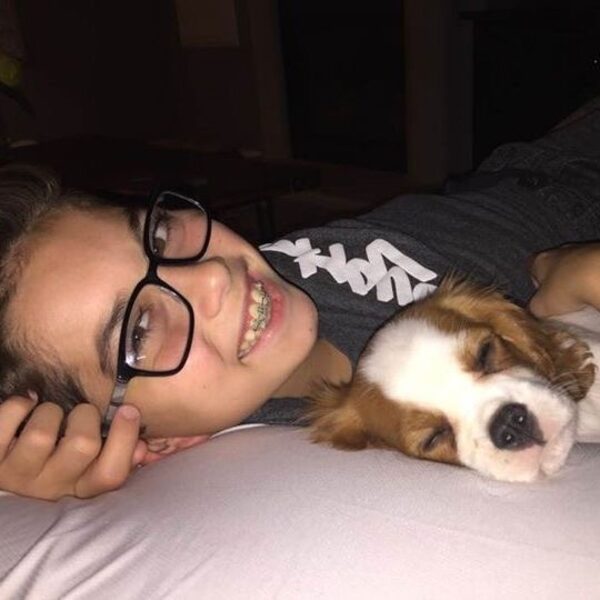 A girl cuddling her Cavalier puppy in bed